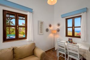 a living room with a couch and a table and windows at Villa Ftenagia in Halki