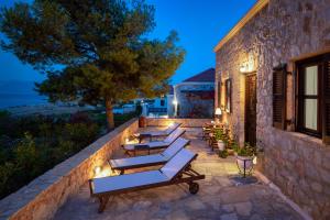 a row of lounge chairs on a stone wall at night at Villa Ftenagia in Halki