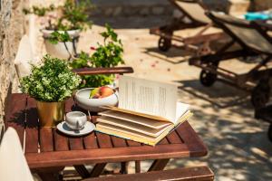 a table with a book and a bowl of fruit and a cup at Villa Ftenagia in Halki