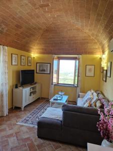 a living room with a couch and a tv at Country Apartment with View of the Tuscany Hills in Peccioli