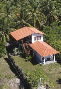 a small house with an orange roof and palm trees at Casastral Atins in Barreirinhas