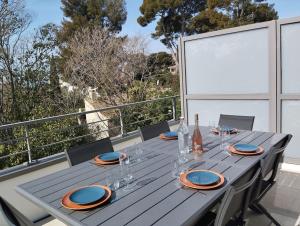 a wooden table with plates and glasses on a balcony at Appartement 3 chambres, piscine, 50 m des plages in Les Lecques