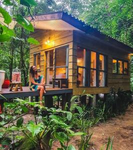 a woman sitting on a bench in front of a tiny house at LUGAR PERFEITO in Boicucanga