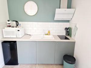 a white kitchen with a sink and a microwave at Les logements de Laura in Saint-Maur +7 photos