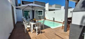 a patio with a table and chairs and an umbrella at casa confortável piscina privativa in Camaçari