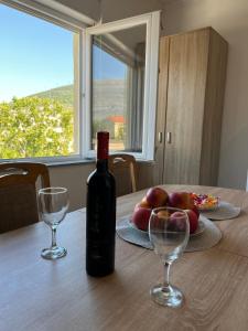 a bottle of wine sitting on a table with two glasses at Apartman Spaja in Trebinje