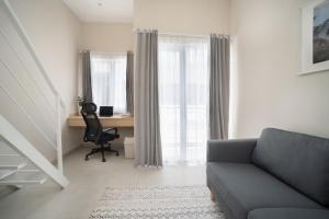 a living room with a couch and a desk and window at Bali Bustle Sunset Coliving and Coworking Space in Legian