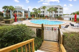 a pool with a wooden fence and chairs and a house at Hibiscus H204 in St. Augustine