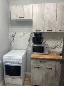 a kitchen with a white stove and a microwave at 1-ная Квартира Орбита in Rakhat