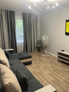 a living room with a couch and a fan at 1-ная Квартира Орбита in Rakhat +9 photos