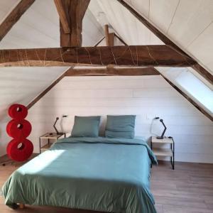 a bedroom with a blue bed in a attic at maison de caractère la petite madeleine in Saint-Laurent
