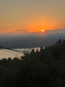een zonsondergang boven een watermassa met de zon in de verte bij Veramente Villas With Sea view in Lefkada