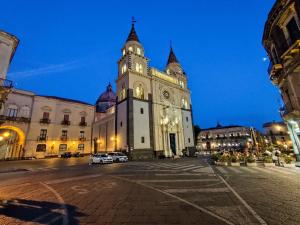 Un gran edificio con una torre de reloj por la noche. en La Casa Di Via Marzulli, en Acireale 36 fotos más