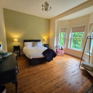 a bedroom with a bed and a desk and two windows at Quilly Farm House - North Coast - Entire House, near Castlerock, Coleraine, Beach walks, countrywalks, golf courses in Articlave