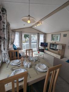 a dining room table with plates and glasses on it at LOVELY BRIGHT AND AIRY CARAVAN ON THE 5 Star SHOREFIELD COUNTRY PARK ENTERTAINMENT PASSES INCLUDED in Milford on Sea