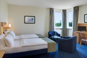 a hotel room with a bed and a chair at IntercityHotel Stralsund in Stralsund