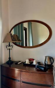 a mirror on top of a dresser with a lamp at Two Flowers Hotel in Pedoulas
