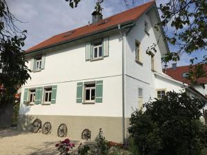 una casa bianca con tetto rosso e finestre verdi di ehemaliges Bauernhaus a Erkenbrechtsweiler