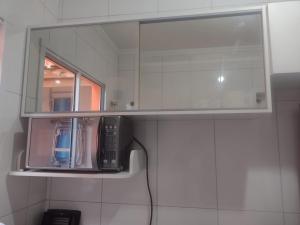 a microwave sitting on a shelf under a mirror at Cantinho do descanso in Bertioga +35 photos