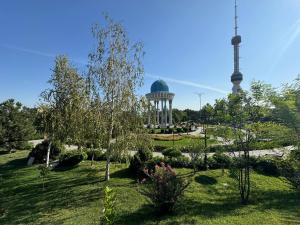 a garden with a building and a tower in the background at Comfortable apartment in Tashkent in Yunusobod