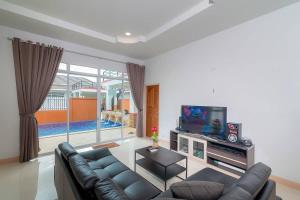 a living room with a couch and a tv at บ้านชิดหัวหินพูลวิลลา in Khao Tao
