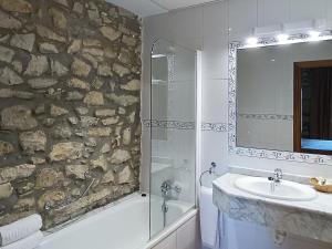 a bathroom with a stone wall and a sink and a shower at Hotel Casona Los Caballeros in Santillana del Mar +52 photos