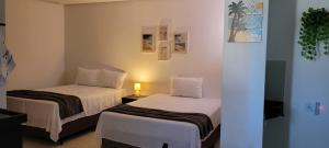Zimmer mit 2 Betten und einer Lampe auf einem Tisch in der Unterkunft Águas da Barra in Maragogi