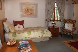 a bedroom with a bed and a table and a chair at Plotsklaps Self Catering Cottage in Tokai