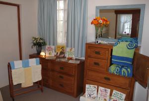 a bedroom with a dresser and a dresser with a mirror at Plotsklaps Self Catering Cottage in Tokai