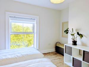 a white bedroom with a bed and a window at Victorian Town House - Sleeps 6 in Tywyn
