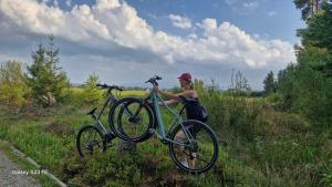 a woman is holding a bike in a field at Apartament u Chowańców (blisko baseny termalne) in Bańska Niżna