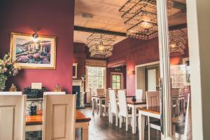 une salle à manger avec des murs rouges, des tables et des chaises dans l'établissement The Salwey Arms, à Ludlow