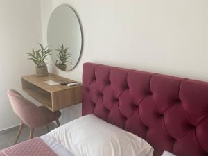 a bedroom with a purple padded headboard and a table at Margarita's apartment 4 in Nea Peramos