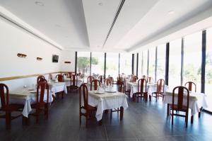 a dining room with tables and chairs and windows at Apartamento Equitare Rural na Serra de Lousã in Miranda do Corvo