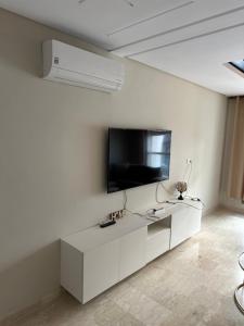 a white living room with a flat screen tv on a wall at Luxury apartment Malabata hills in Tangier
