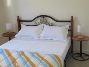 a bed with white pillows and two lamps on tables at Résidence Séjour Téranga in Saint-Louis