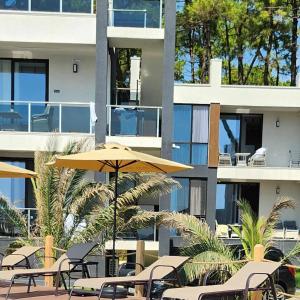 a patio with chairs and an umbrella and a building at Sun Beach Hotel Grigoleti in Grigoleti