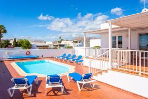 a swimming pool on a patio with chairs and a house at Villa Adella in Tías