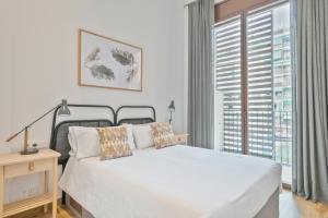 Un dormitorio con una cama blanca y una ventana grande. en Aspasios Arc de Triomf Apartments, en Barcelona