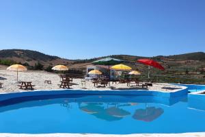 a swimming pool with chairs and umbrellas on a beach at PH in Alto Douro Vinhateiro in Urros