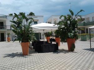 un patio con mesas, sombrillas y macetas en Residence Cala Verde, en Marina di Mancaversa