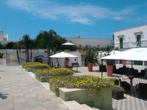 un patio con mesas, sombrillas blancas y flores en Residence Cala Verde, en Marina di Mancaversa