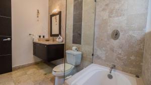 a bathroom with a toilet and a sink and a tub at Playa Village Condo by BVR in Playa del Carmen