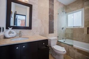 a bathroom with a toilet and a sink and a mirror at Playa Village Condo by BVR in Playa del Carmen
