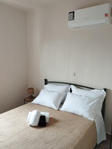 a bed with white pillows and a towel on it at Aloe Apartments Syros in Lazaréta
