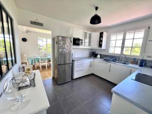 a kitchen with white cabinets and a stainless steel refrigerator at Maison familiale La Fontaine tout confort à 400m de la plage in Plobannalec-Lesconil