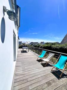 two chairs and a table on a wooden deck at Maison familiale La Fontaine tout confort à 400m de la plage in Plobannalec-Lesconil