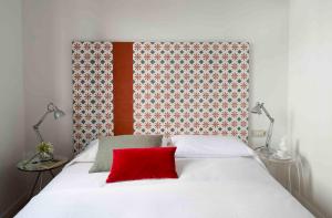 a bedroom with a white bed with a red pillow at Eric Vökel Boutique Apartments - BCN Suites in Barcelona