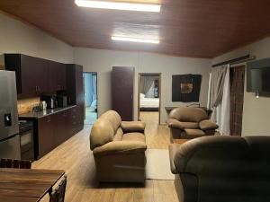 a living room with chairs and a kitchen with a bed at 72 on Devenish in Polokwane