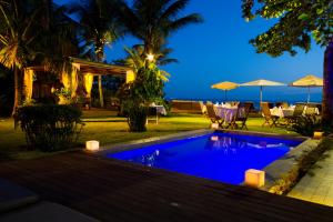 a villa with a swimming pool at night at Hotel Spa Nau Royal in Camburi